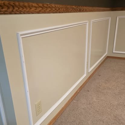 Interior wainscoting with styled decor — white panel corner with dark accent walls and Nebraska memorabilia